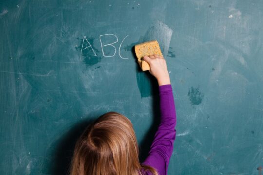 A close-up of a student wiping and cleaning the chalkboard.