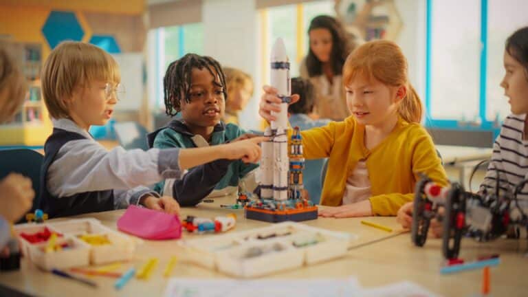 Students sit at a table, building a rocket as part of a STEM lesson.