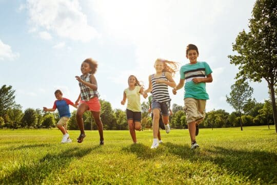 A group of students run around outside, all of them smiling and having fun.