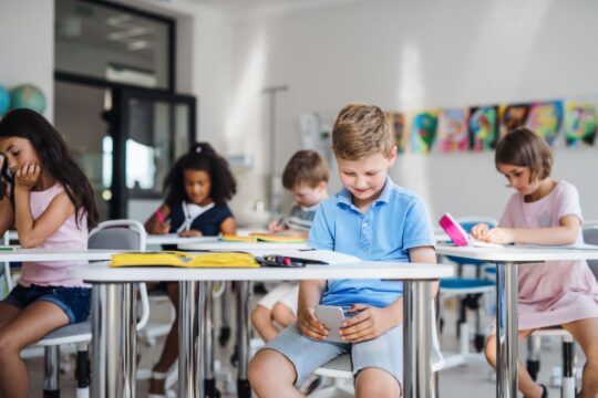 A student looks at his phone under his desk instead of listening.