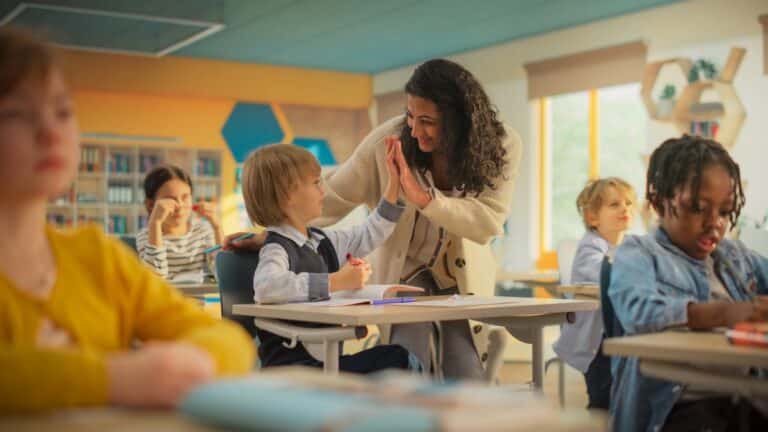 A teacher and student high-five in the classroom.