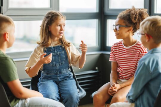 A group of students sit together in a circle and talk.