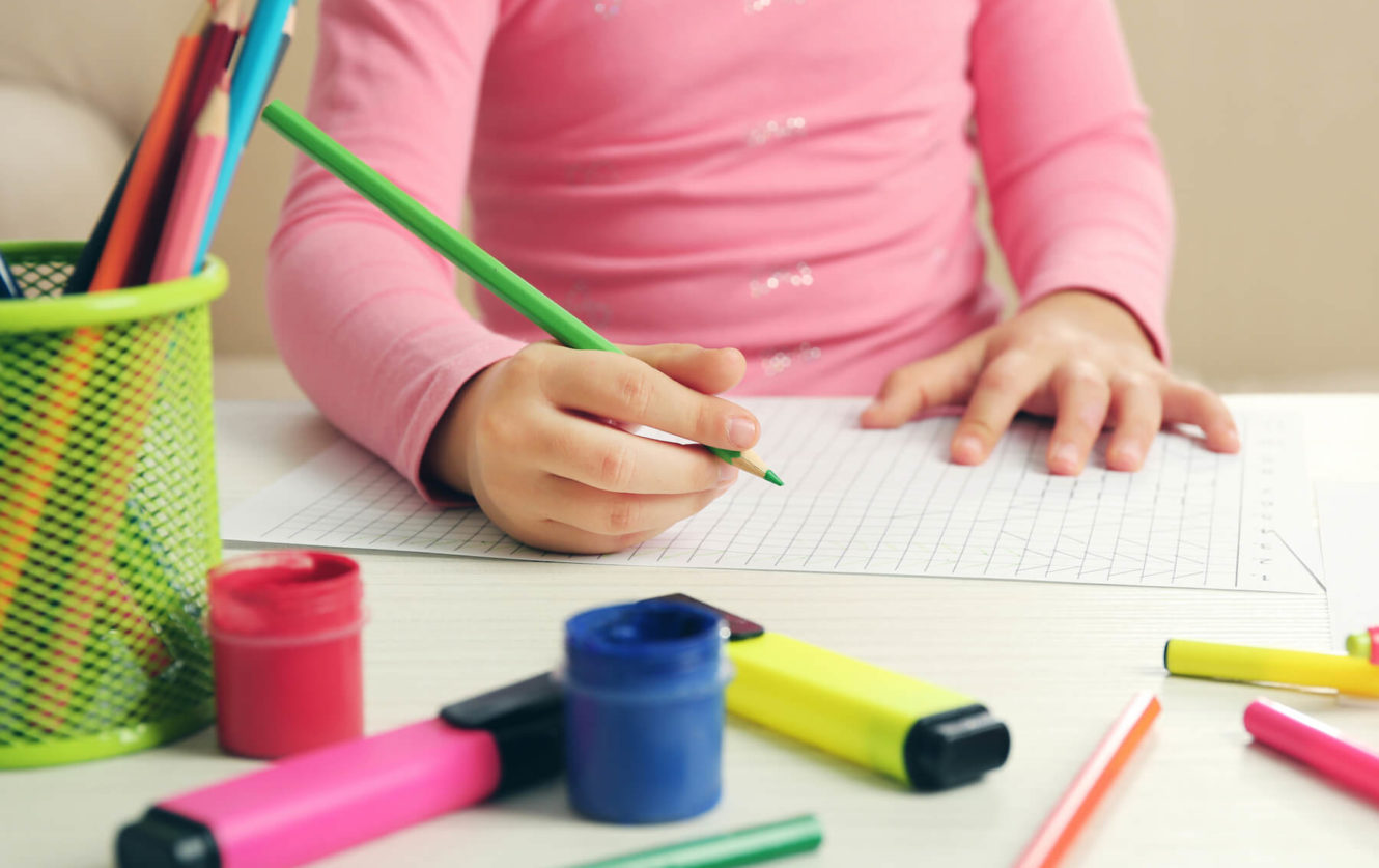 Close up of young girl drawing on graph paper