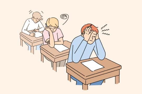 Three anxious students sit at their desks doing schoolwork.