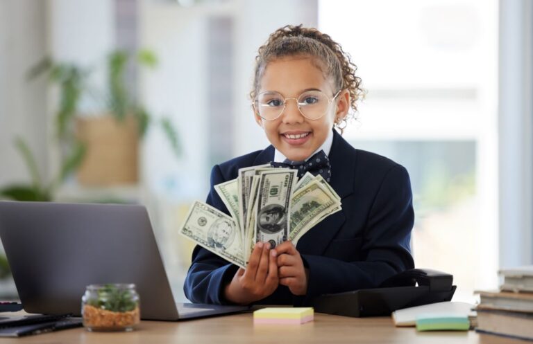 A young girl sits in a suit and fans out her paper money.