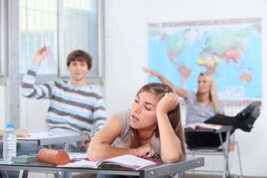 Three students throwing stuff and displaying disruptive behavior in the classroom.