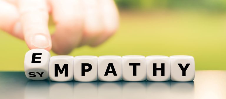 Hand turns dice and changes the word “sympathy” to “empathy.”